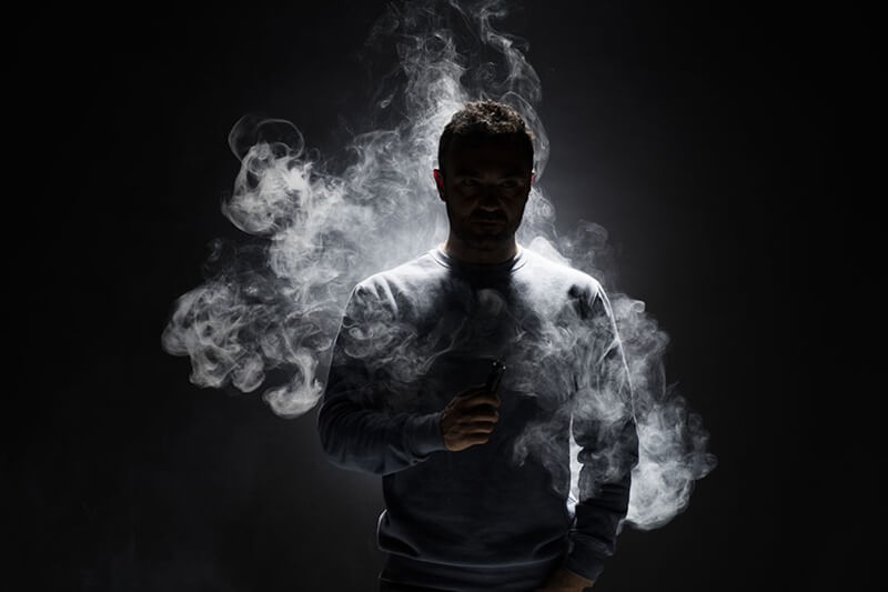 Homem com cigarro eletrônico em mãos mostrando que sabe os efeitos colaterais do vape com nicotina